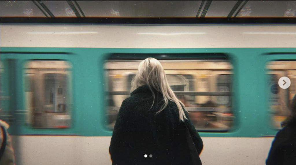 Une femme de dos face au métro parisien qui défile devant elle