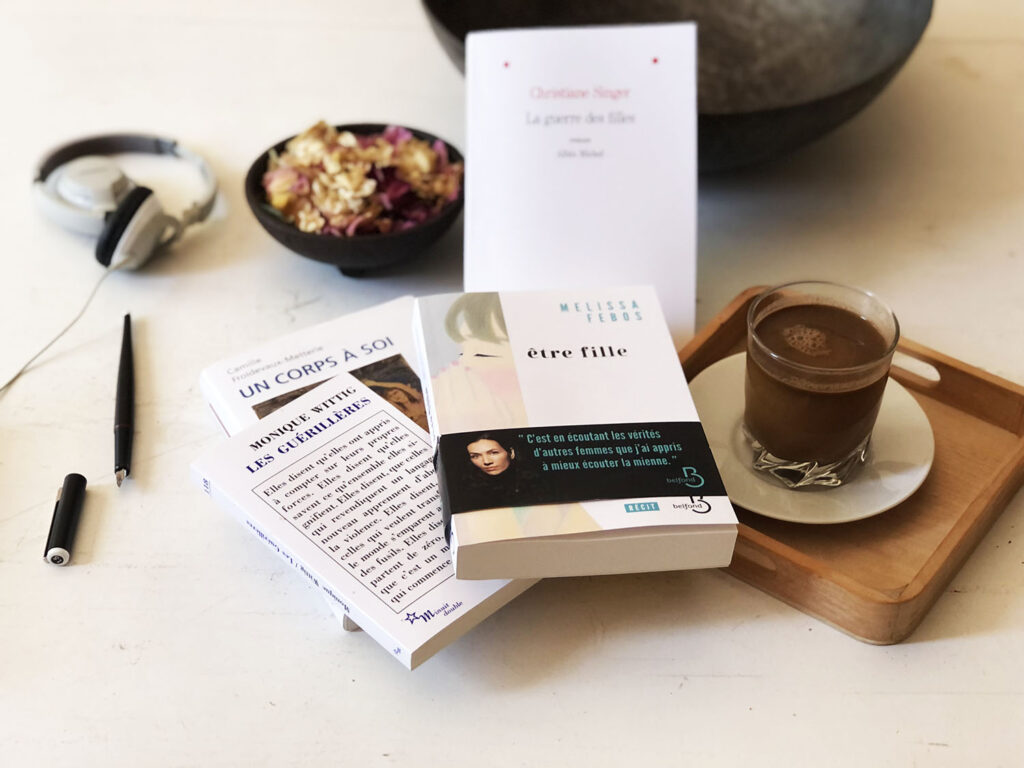 une pile de livres posés à côté d'un verre de café au lait. Au centre le livre être fille de Melissa Febos