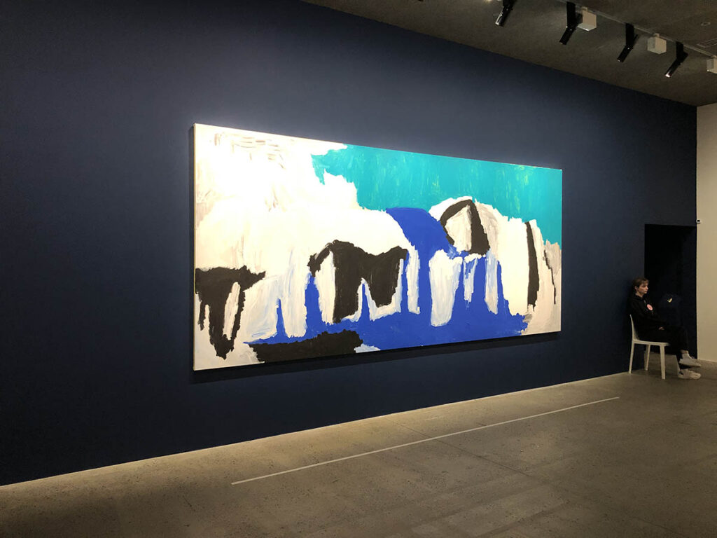 Peinture de Sally Gabori bleue et noire exposée sur un mur bleu marine à la Fondation Carrier