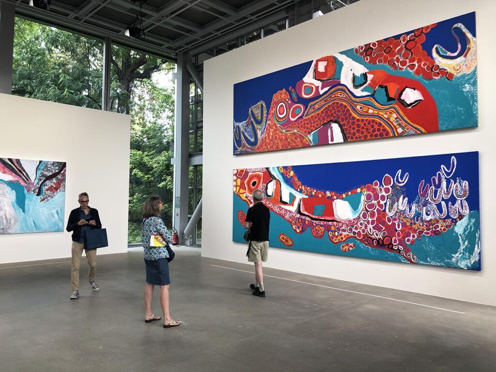 Trois grande toiles de la peintre Sally Gabori exposées sur un mur blanc à la Fondation Cartier de Paris