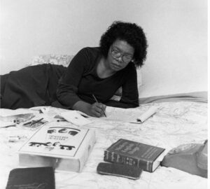 Maya Angelou allongée sur son lit en train d'écrire à la main, en 1982, dans une chambre d'hôtel.